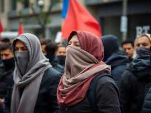 Oameni cu fețele acoperite, demonstrând în stradă.